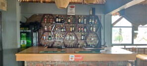 A bar area with a wooden counter and a brick wall. There are multiple shelves with bottles, and a sign indicating card payments are accepted.
