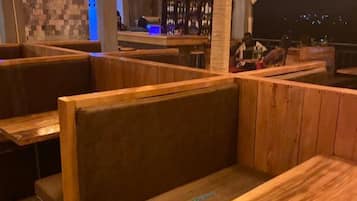Un restaurante con cabinas y mesas de madera, iluminación colgante y una zona de bar al fondo.