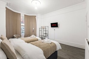 A hotel room with two beds, a TV, and a window with curtains. - Luxury Garden Apartment 2Bed 2Bath Nottingham (Nottingham)