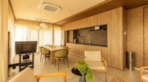 Una cocina moderna con comedor, muebles de madera, estufa integrada y televisor.