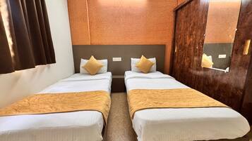 A hotel room with two beds, a wooden headboard, a mirror, and a window with curtains.