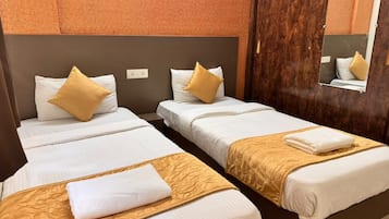 Una habitación de hotel con dos camas individuales, cada una con un colchón blanco y un cabecero marrón. Hay dos almohadas en cada cama, una blanca y una dorada. La habitación tiene un cabecero de madera y un espejo en la pared.