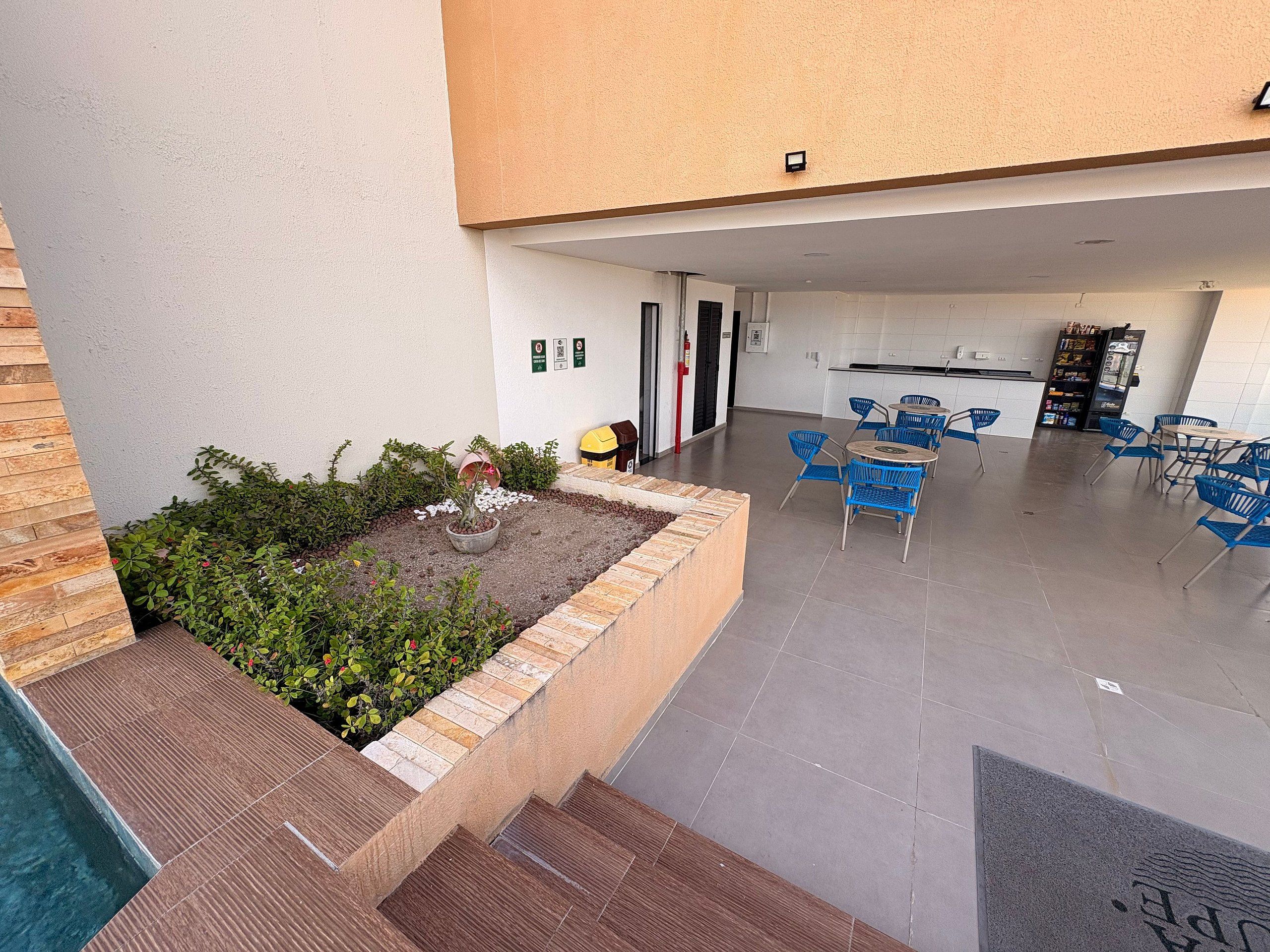 A modern outdoor seating area with blue chairs and a small garden with plants and a decorative element.