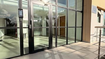 Entrada de un edificio con puertas de vidrio, un teclado de seguridad y suelo de baldosas.