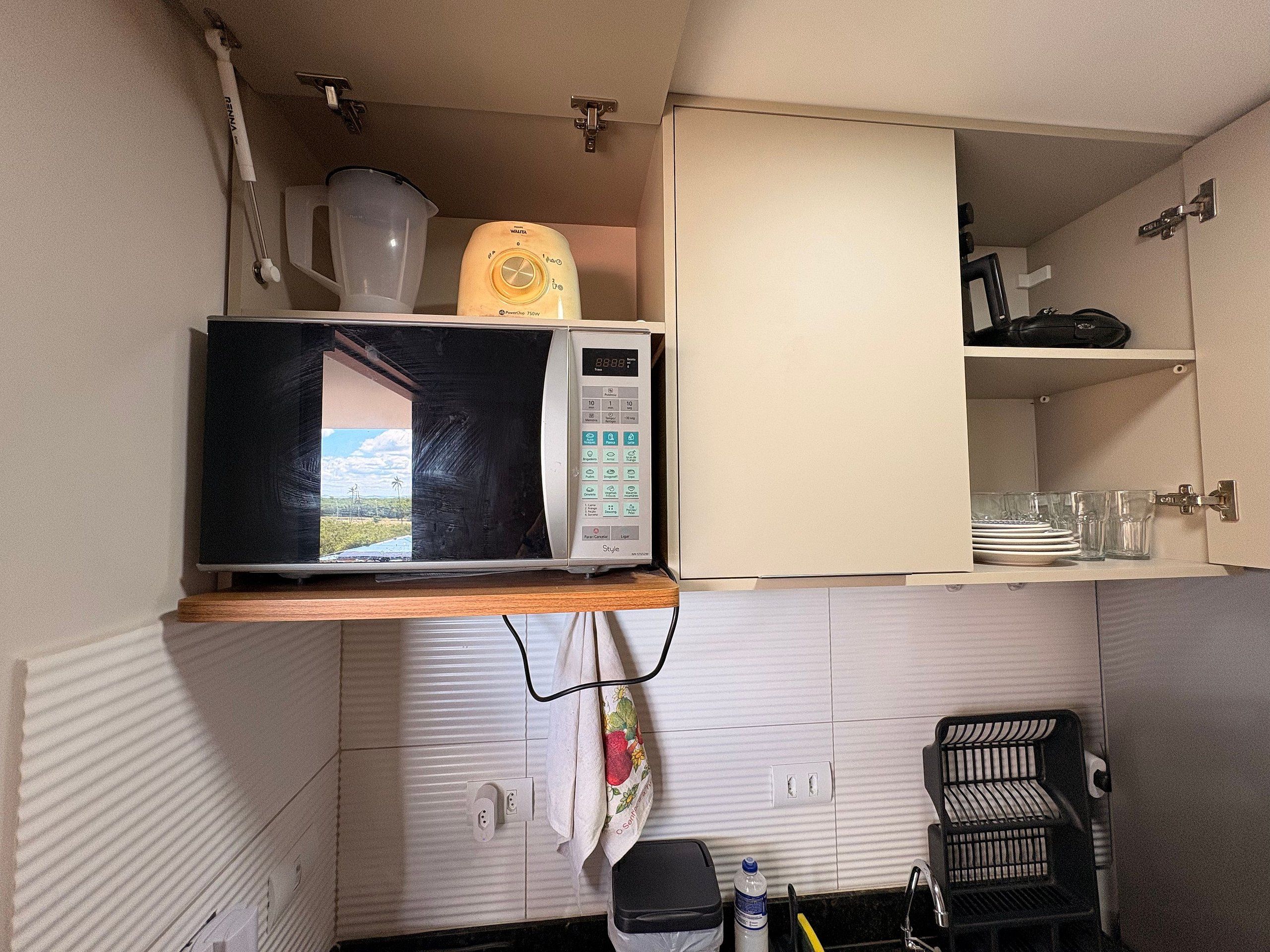 Una cocina con microondas, dispensador de agua y pileta.
