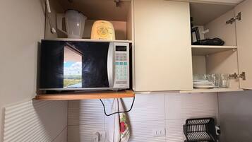 Una cocina con microondas, dispensador de agua y pileta.