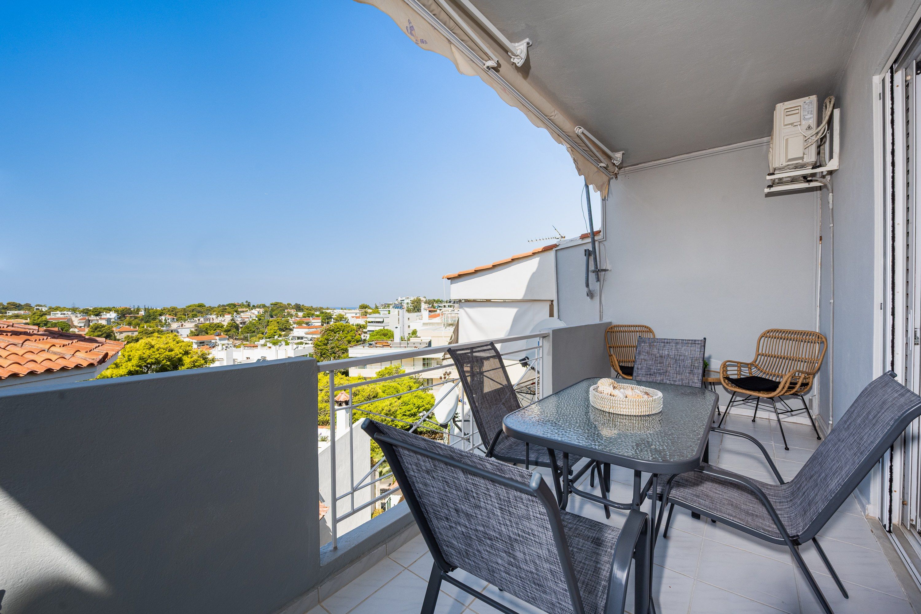 A balcony with a table and chairs, overlooking a residential area.