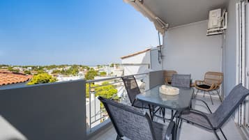 A balcony with a table and chairs, overlooking a residential area.