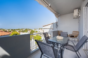 A balcony with a table and chairs, overlooking a residential area.