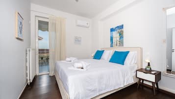 A hotel room with a bed, a nightstand, a mirror, a window with curtains, and a wall with a painting.