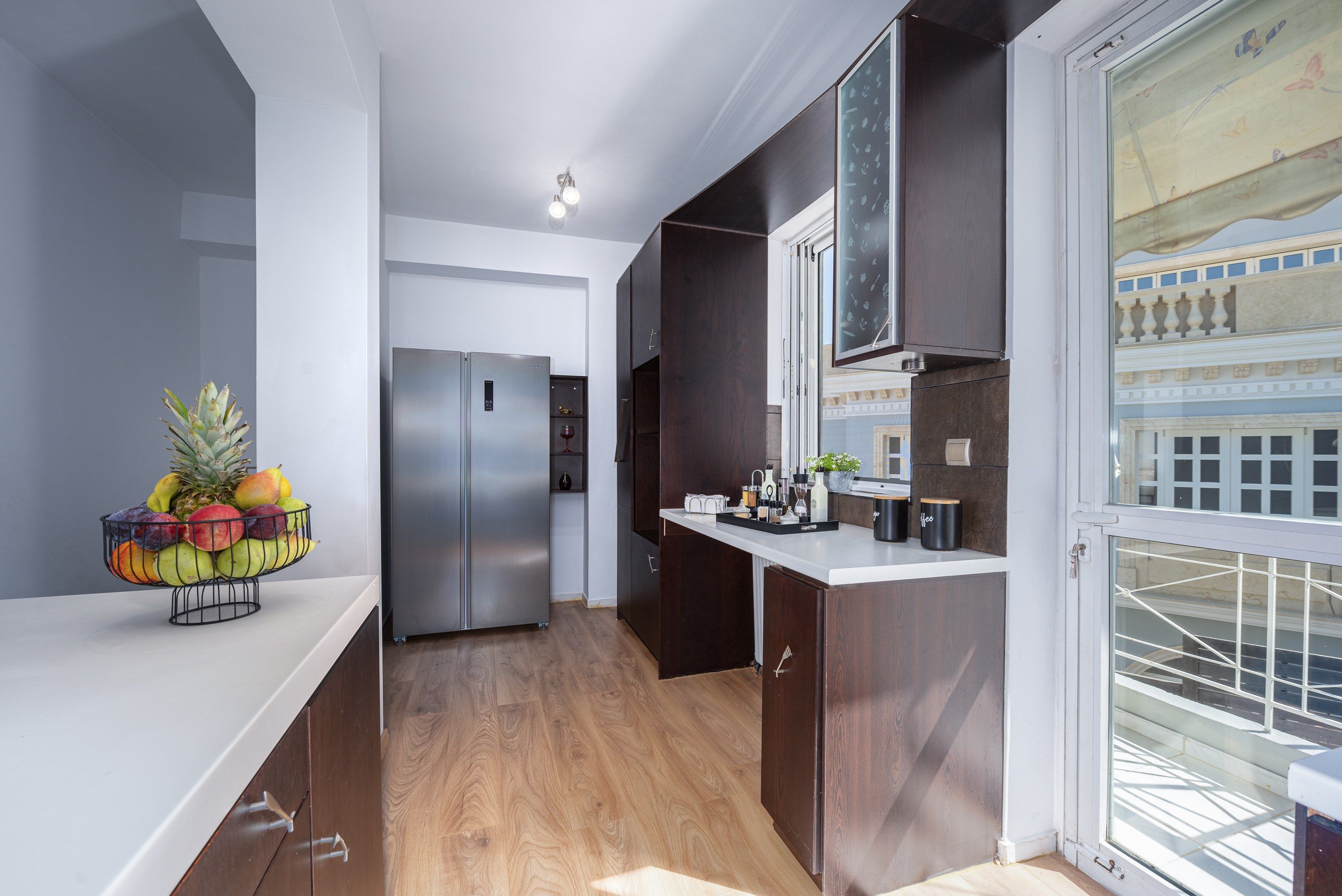 A modern kitchen with a stainless steel refrigerator, wooden cabinets, and a fruit bowl on the counter.