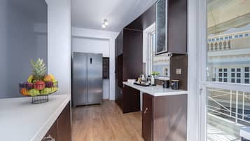 A modern kitchen with a stainless steel refrigerator, wooden cabinets, and a fruit bowl on the counter.