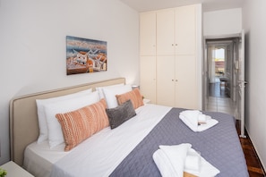A hotel room with a bed, a painting, and a view of the outside.