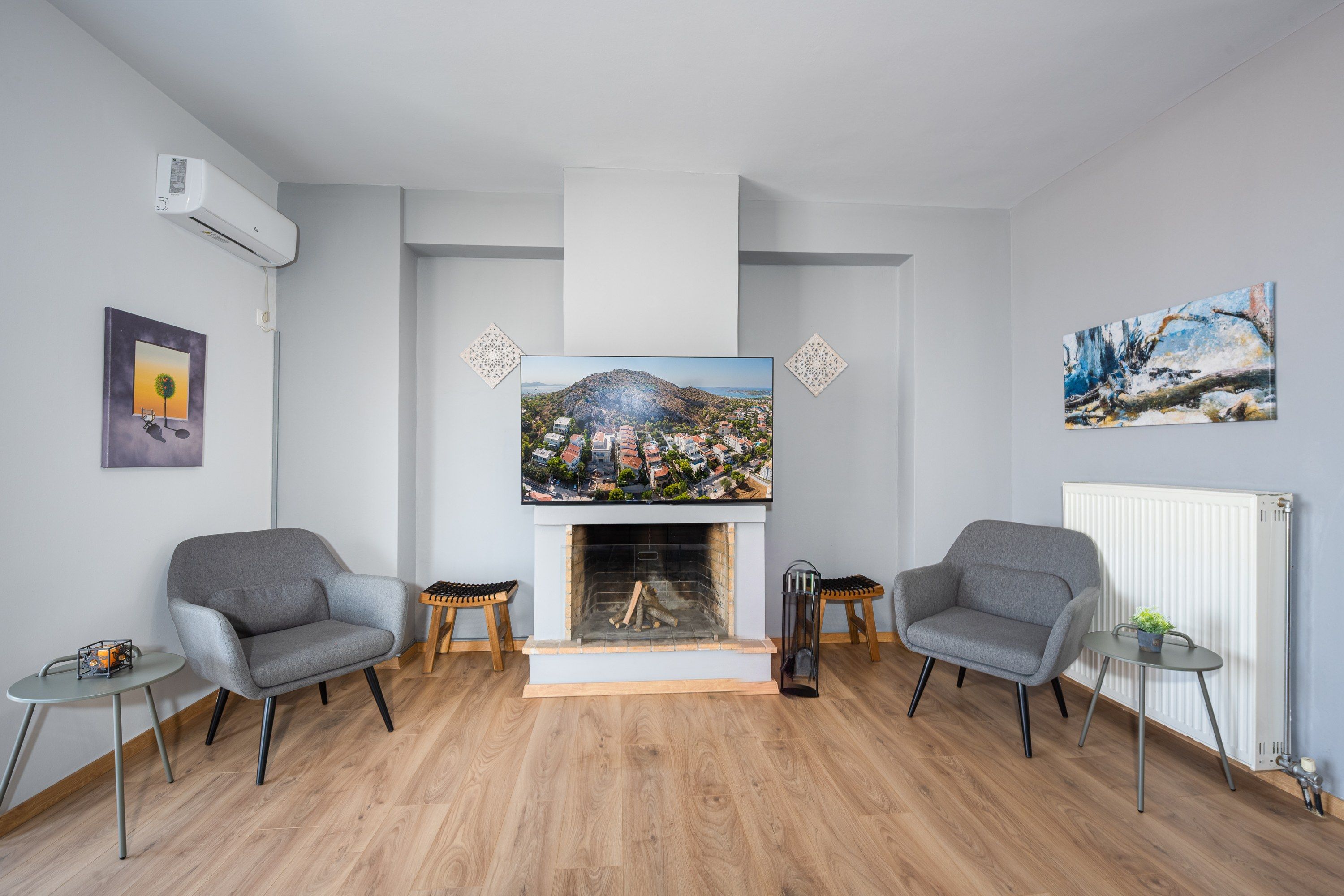 Una sala de estar con chimenea, dos sillones, una mesa de centro y obras de arte en las paredes.