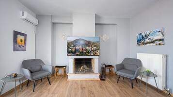 Una sala de estar con chimenea, dos sillones, una mesa de centro y obras de arte en las paredes.