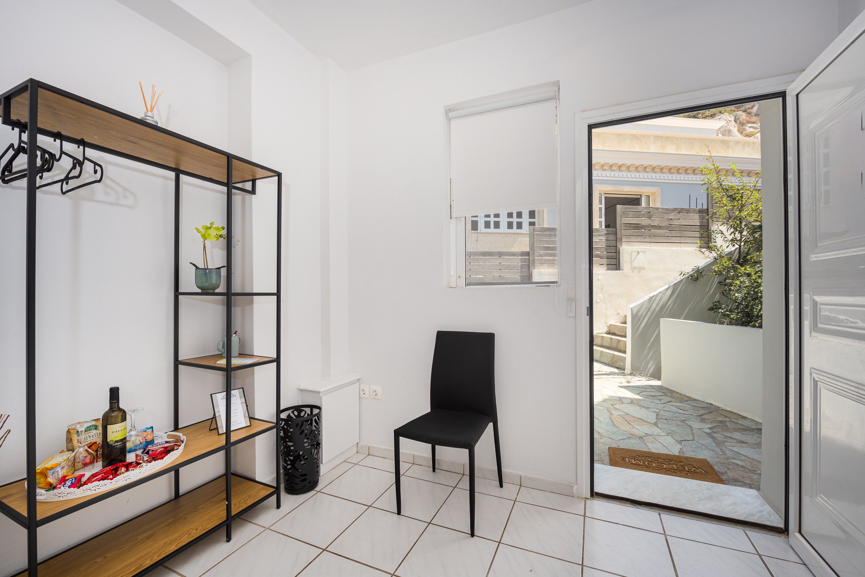 A room with a wooden shelf unit, a black chair, and a door leading outside.