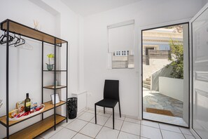 A room with a wooden shelf unit, a black chair, and a door leading outside.