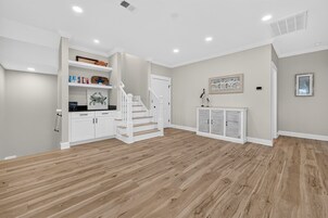 Una habitación amplia con piso de madera, paredes blancas, una escalera y un armario empotrado con puerta.