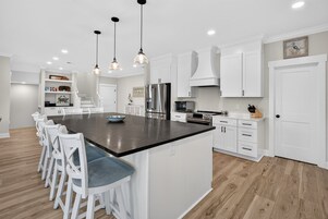 Una cocina moderna con una isla central, muebles blancos y piso de madera.