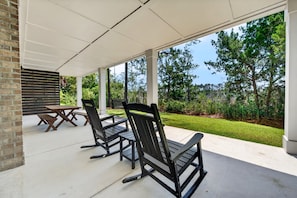 Área de varanda coberta com móveis de exterior e vista para um jardim paisagístico.