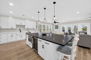 Una cocina moderna con muebles blancos, una isla central e iluminación colgante.