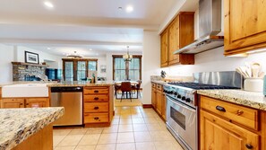 A modern kitchen with granite countertops, wooden cabinets, a stainless steel range, and a dishwasher. - Snowcreek Vi The Lodges #1153 2 Bedroom Condo (Mammoth Lakes)