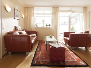 A living room with two leather sofas, a coffee table, and a rug. - Holiday Apartment in Norderney With Wi-fi (Norderney)