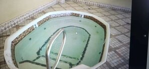 Una piscina con bordo piastrellato e scala in metallo.