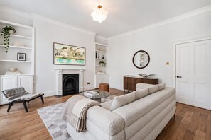A living room with a fireplace, a sofa, a coffee table, and a bookshelf. - Spacious Notting Hill 3-bed With a Home Office (London)