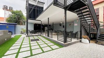 Un edificio moderno con una zona de estar al aire libre techada, una escalera y un pequeño jardín.