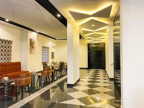 A hotel lobby with a checkered floor, a seating area with chairs and a sofa, and a modern ceiling design with recessed lighting. - Tzar Vidson Luxury Hotel And Suites (Abuja)