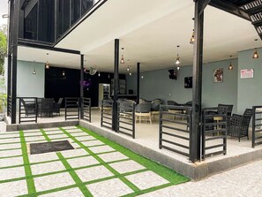 An outdoor seating area with chairs and tables, a covered section with a ceiling fan, and a checkered floor pattern. - Tzar Vidson Luxury Hotel And Suites (Abuja)