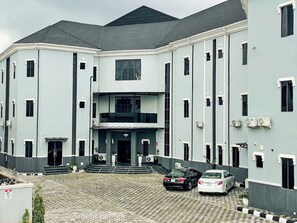 A multi-story building with a central entrance, a staircase leading to the entrance, and a paved driveway. - Tzar Vidson Luxury Hotel And Suites (Abuja)