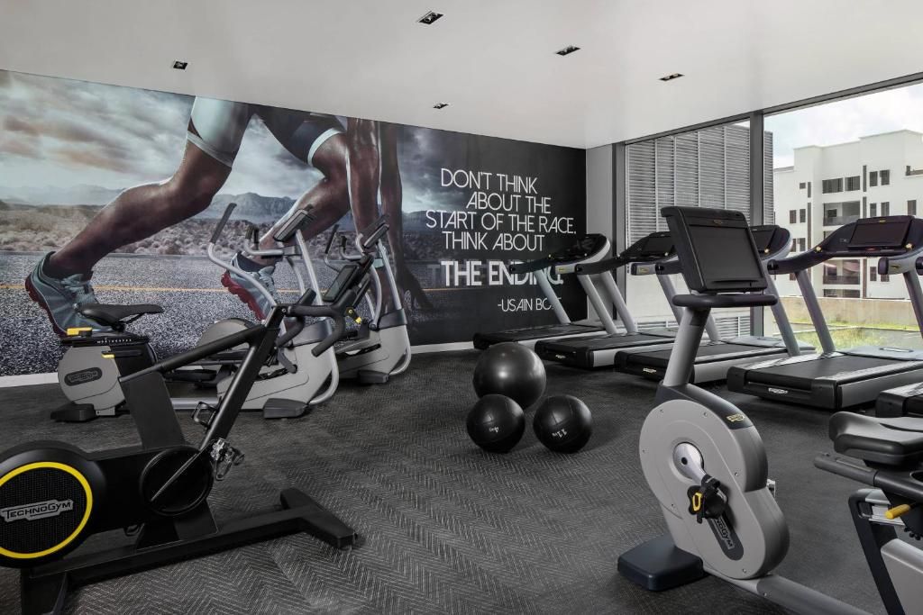 A gym with exercise equipment, a motivational quote on the wall, and large windows.