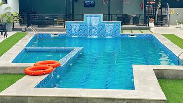 Una piscina con borde de azulejos y una sección separada con un diseño de mosaico diferente. Hay dos flotadores salvavidas en el borde de la piscina.