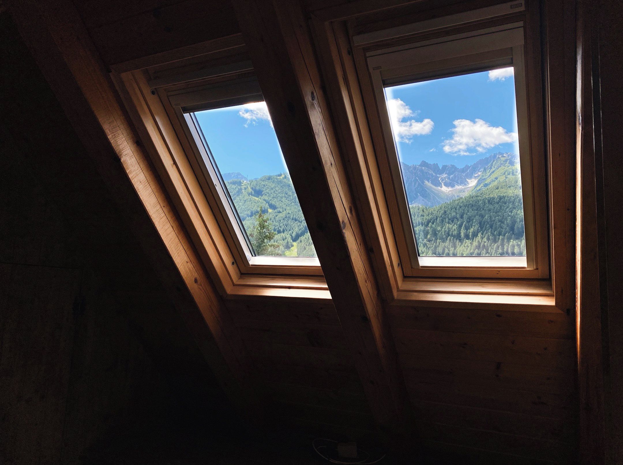 A room with two skylights offering views of a mountainous landscape.