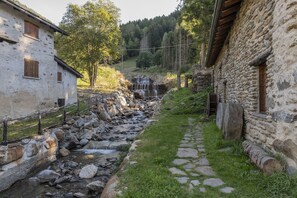 Edifici de pedra rústic amb un camí de pedra que condueix a una petita cascada.