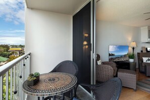 Ein Balkon mit rundem Tisch und Stühlen, einer Schiebetür und Blick auf die Landschaft.
