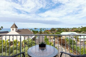 Un balcon avec vue sur une église, une route et la côte.