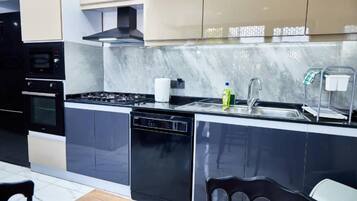 A modern kitchen with a stove, oven, dishwasher, and a sink with a faucet.