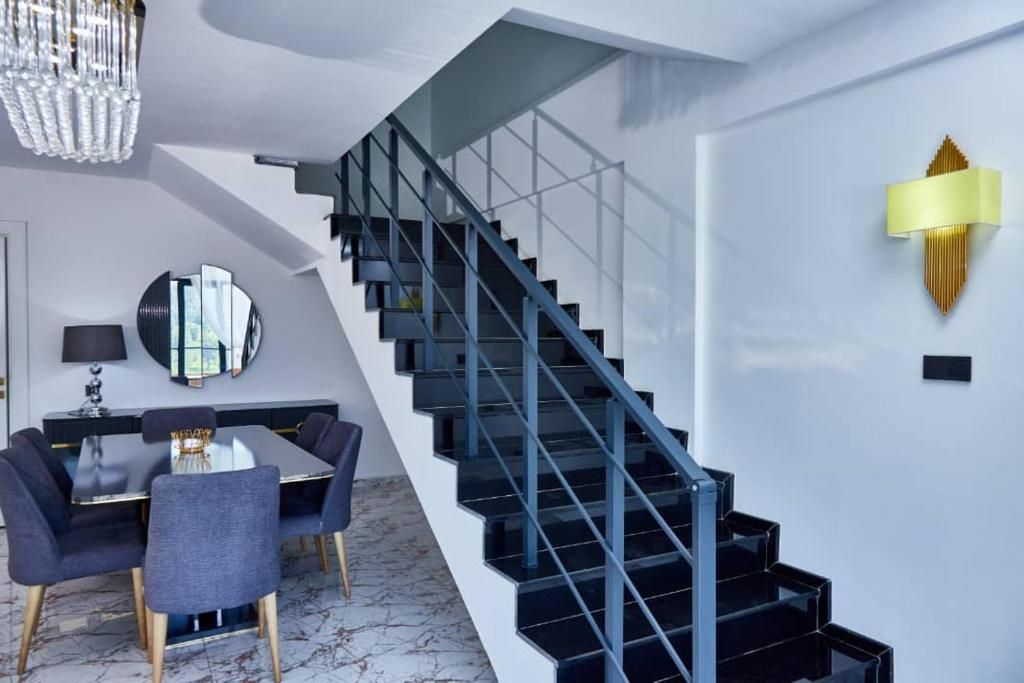 A modern interior with a staircase, a dining area, and a chandelier.