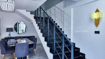 Un intérieur moderne avec un escalier, un coin repas et un lustre.