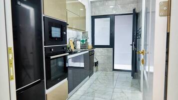 Cocina compacta equipada con refrigerador, microondas, horno y lavavajillas.