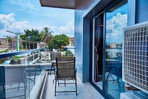 A balcony with a glass railing, a chair, and a table.