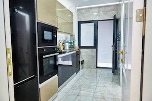 A compact kitchen with a refrigerator, microwave, oven, and dishwasher.