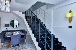 A modern interior with a staircase, a dining area, and a chandelier.