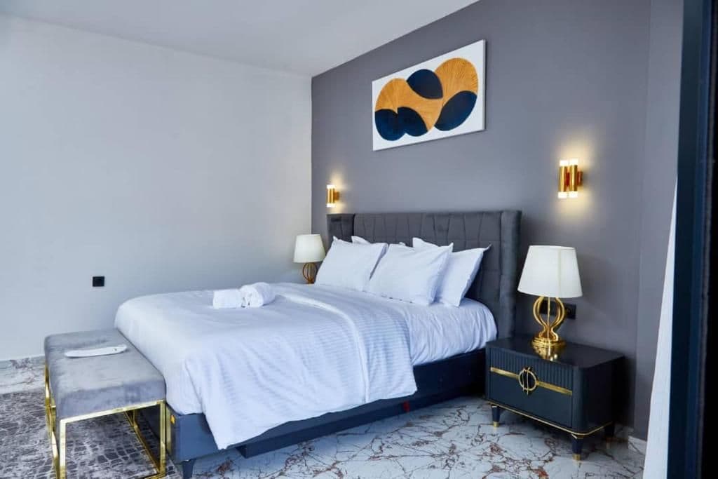 Un dormitorio moderno con cama, mesitas de noche y una obra de arte en la pared.