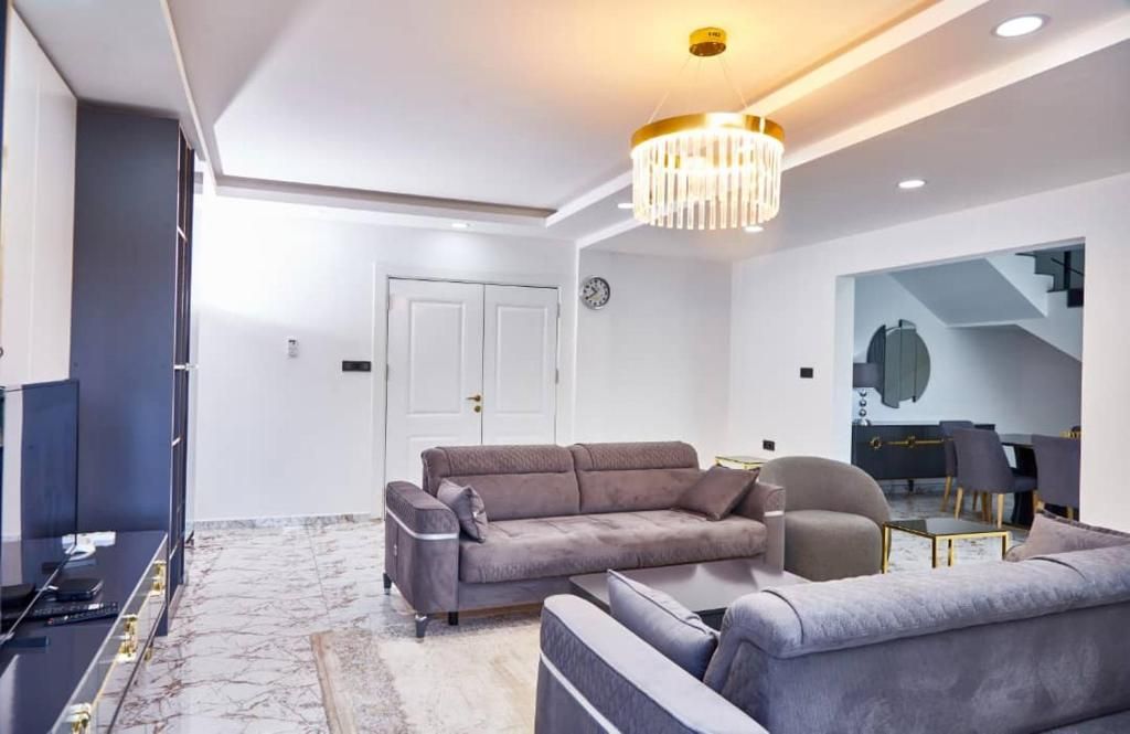 Un salon moderne comprenant un canapé, une table basse et un lustre.