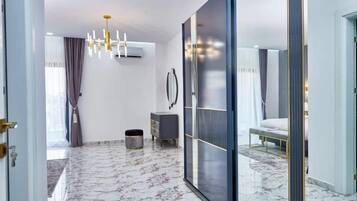 A modern bedroom with a large sliding door, a bed, a bedside table, and a small cabinet.