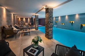 A modern indoor pool area with lounge seating, a stone pillar, and a book on a table. - L'Abura - Les Gets - Village Center (Les Gets)